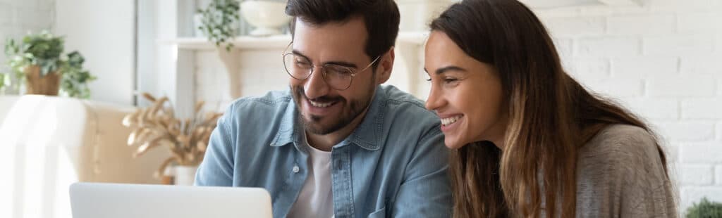 couple laughing and looking at a computer